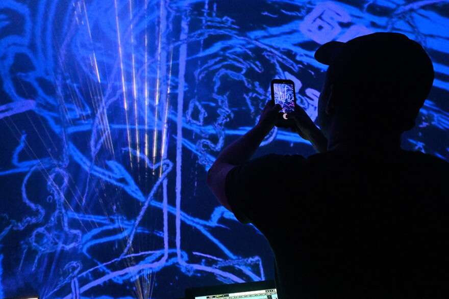 S.C.A.M.S. co-owner Justin Moore takes a video from the control booth during a free rave S.C.A.M.S. and GRIFT raves hosted at the Challenger Learning Center's planetarium on Sept. 11.