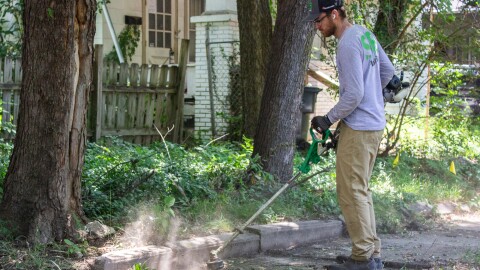 SB Mowing owner Spencer edges a sidewalk while working in a Wichita neighborhood on Friday afternoon.