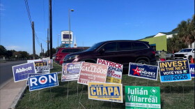 Campaign signs are shown outside Las Palmas Library on the first day of early voting for the 2026 midterm election.