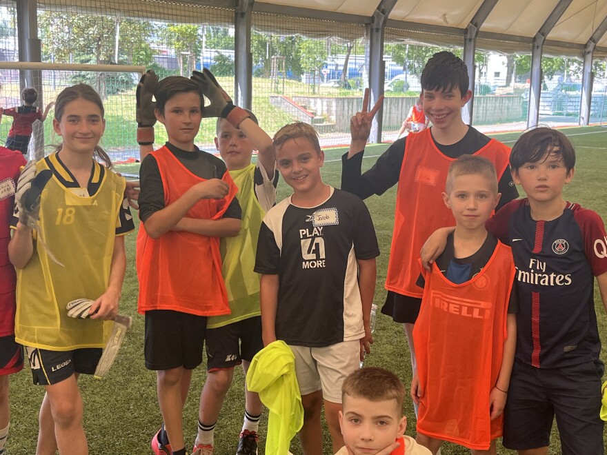  Ukrainian refugee kids pause their soccer game pose for a group photo
