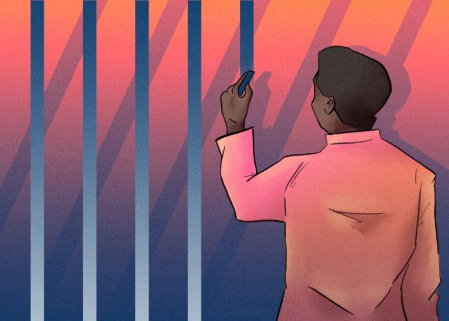 A person in a pink shirt, possibly a detainee unfit for trial at Menard County Jail, holds a blue marker and draws vertical lines on a gradient background transitioning from orange to blue. The scene is viewed from behind the person.