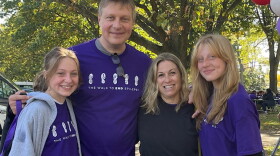 Four people standing together, all wearing purple shirts with hard-to-see messages about epilepsy