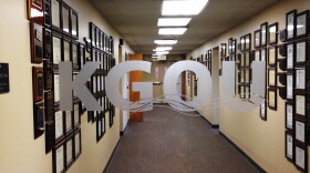 Looking through the glass door into a hallway with plaques and certificates displayed on the walls.