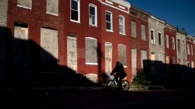 A man rides a bike past boarded up row houses in the Broadway East neighborhood on October 14, 2020, in Baltimore, Maryland. - Demon Lane says his east Baltimore neighborhood will still be blighted by drug dealing, deadly gunfire, rat-infested vacant houses and hopelessness, no matter who wins America's presidential election in November. His area is overwhelmingly Black, deeply poor and devastated by decades of neglect, which stands in stark contrast to the pricey condos, new stores and safe streets a few miles away in overwhelmingly white and affluent areas. 