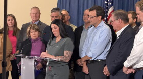 Gov. Bob Ferguson stands with residents and officials as local homeowner describes destruction left behind in summer wildfires. 