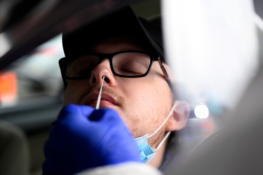 Nathaniel Rivard 20, of Naugatuck leans back as COVID collection specialist Jon Schwartz administers a swab test during Griffin Health's COVID-19 drive-thru testing site at Tunxis community college on November 12, 2020 in Farmington, Connecticut.