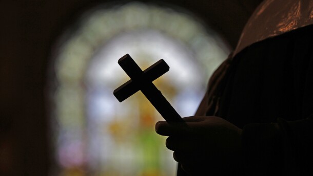 A silhouette of a crucifix framed by a stained glass window