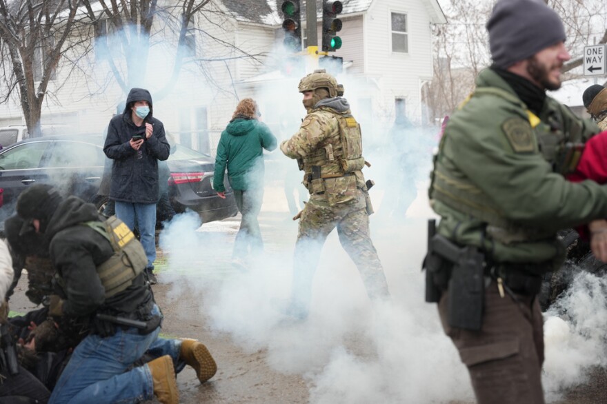 Smoke (tear gas) fills around a crowd.