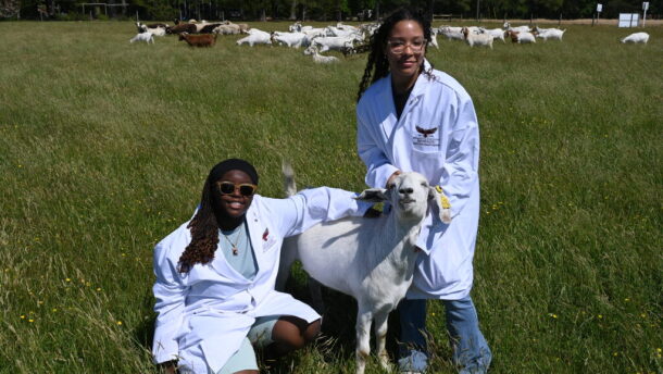 Student vets pose for a picture with a goat