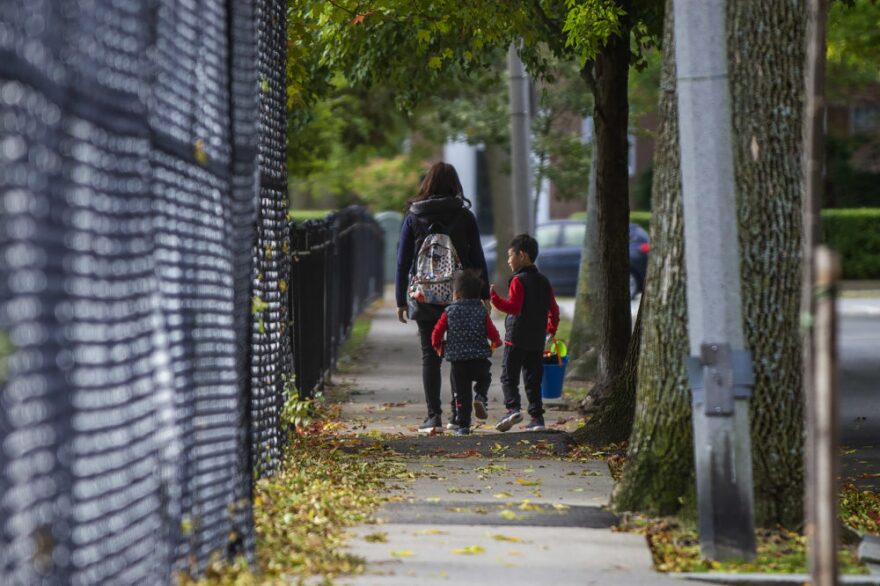 A mother walks with her two children along Still St. as they are on their way to the park at Winthrop Sq. in Brookline. (Jesse Costa/WBUR)