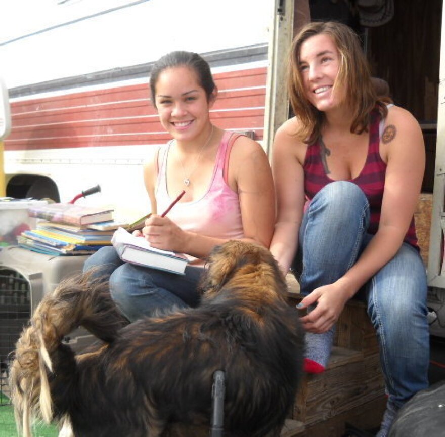 Eighteen-year-old Allie Neill and 20-year-old Eliza Aseltine sit on the front steps of Neill's family's RV in Slab City, Calif. Slab City is an informal, off-the-grid community in the California desert.