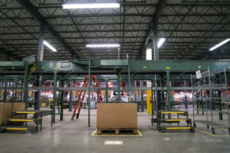 A conveyor belt, one of two types of automation at the Radial warehouse, fetches boxes from the packing station and sorts them by shipping type, depositing them directly into bins with labels like "USPS".