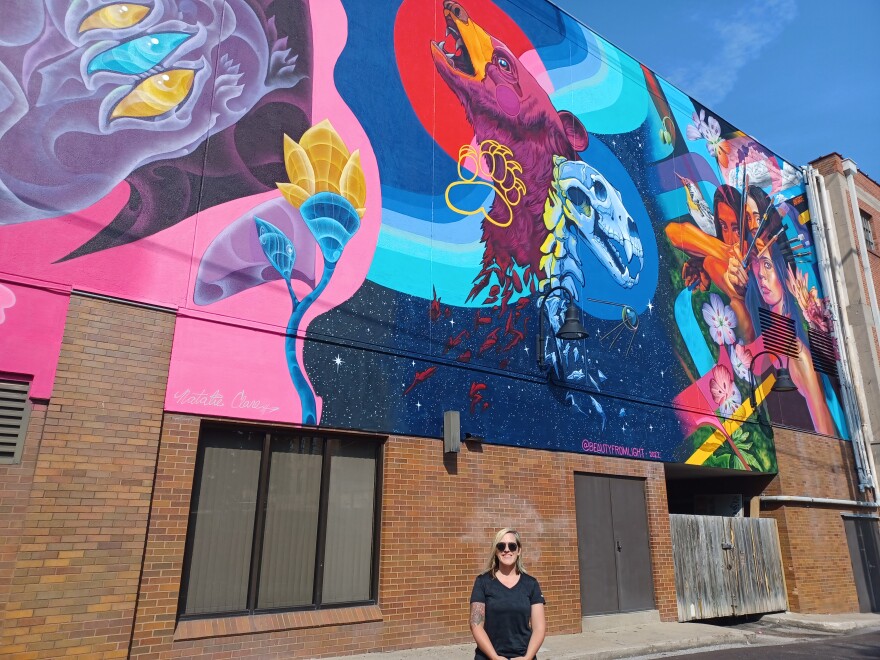 Artist Meg Wagler stands in front of a mural she helped create in downtown Springfield