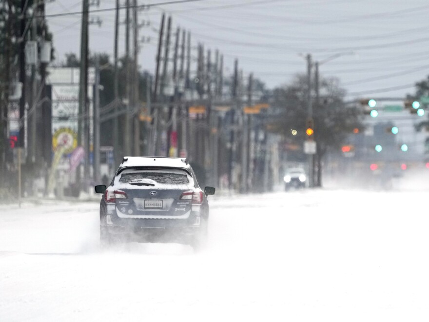 Vehicles drive on snow and sleet covered roads Monday, Feb. 15, 2021, in Spring, Texas. A winter storm dropping snow and ice sent temperatures plunging across the southern Plains, prompting a power emergency in Texas a day after conditions canceled flights and impacted traffic across large swaths of the U.S. (AP Photo/David J. Phillip)