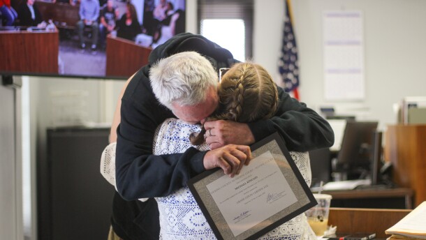 A man hugs a woman. He holds a certificate in his hand that says, "Licking County Municipal Court - H.O.M.E. Court - this certifies that Michael Kincaid has successfully completed the Licking County Municipal Court - H.O.M.E. Court Program and is there awarded the graduate certificate." 