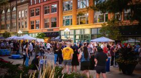 Tons of people stand enjoying the Bruegala on street in Bloomington.