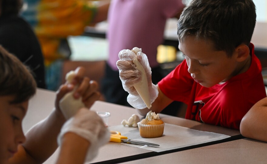 Jack Schalk, a fifth grade student, decorates his cupcake .