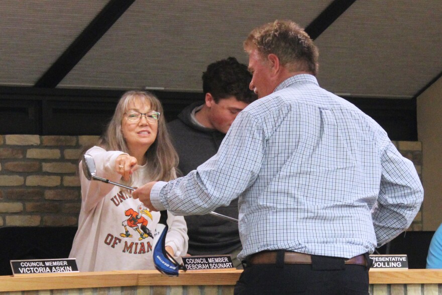 Outgoing Kenai Mayor Brian Gabriel (right) shows off a golf club to Deborah Sounart after his last city council meeting on Wednesday, Oct. 15, 2025 in Kenai, Alaska.