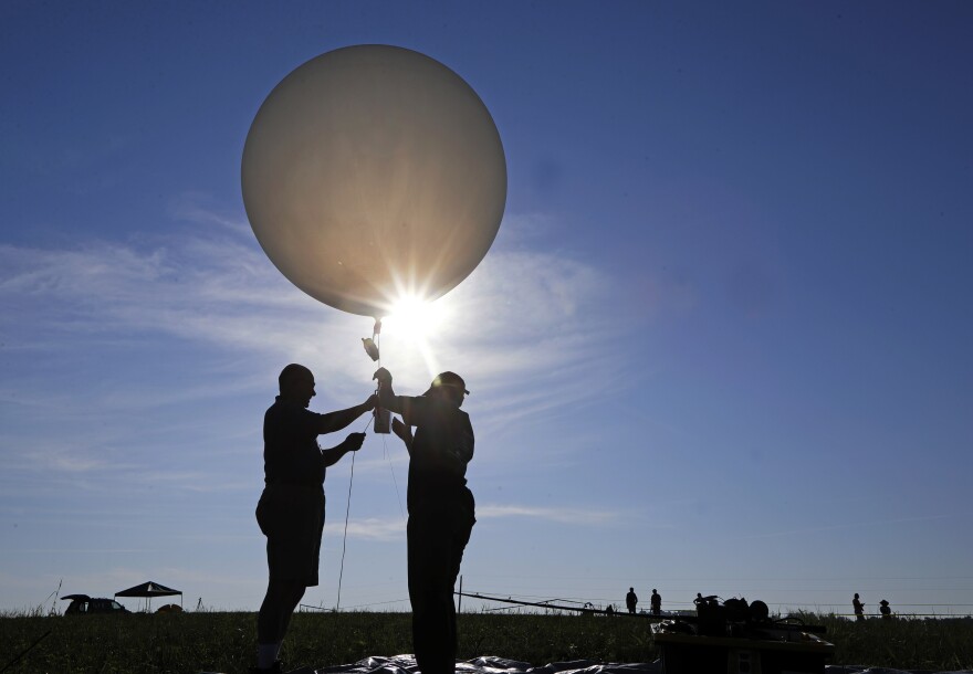 Mike Newchurch, left, professor of atmospheric chemistry at the University of Alabama in Huntsville, and graduate student Paula Tucker prepare a weather balloon before releasing it to perform research during the solar eclipse Monday, Aug. 21, 2017, on the Orchard Dale historical farm near Hopkinsville, Ky. The location, which is in the path of totality, is also at the point of greatest intensity. (AP Photo/Mark Humphrey)