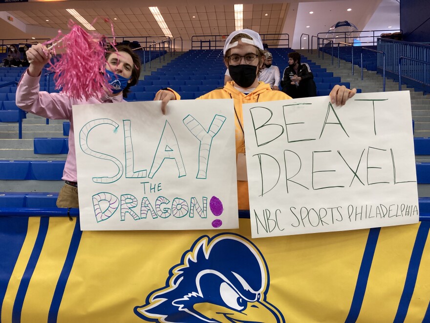 Eric Kramer (left) and another Delaware fan pose with homemade signs prior to women's basketball's Feb. 20 game against Drexel