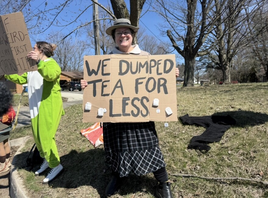 No Kings protester in Kalamazoo, Michigan holds up a sign that says "We dumped tea for less".