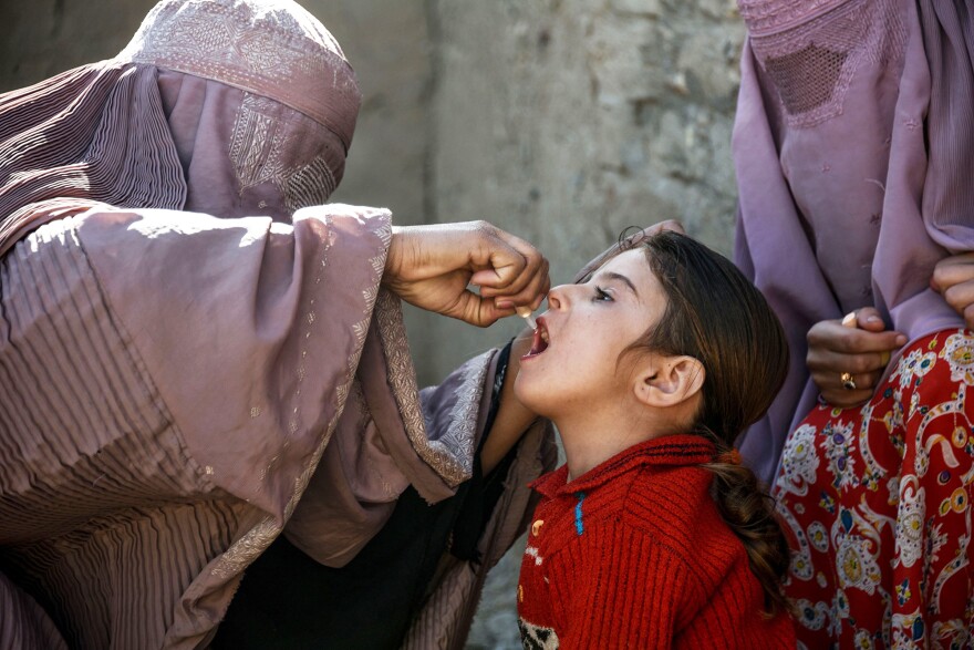 A health worker administers a polio vaccine to a child in Afghanistan's Kandahar province. Taliban opposition to vaccine campaigns have left millions of children unprotected against the virus.