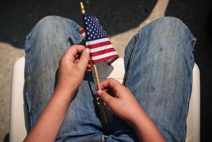 Someone holds an American flag as President Trump speaks at Burning Hills Amphitheatre during the Theodore Roosevelt Presidential Library opening ceremony, Wednesday, July 1, 2026, in Medora, N.D. (Julia Demaree Nikhinson/AP)