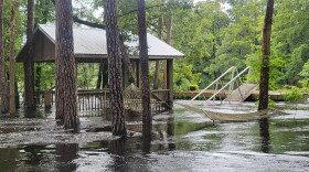 A gazebo next to some hammocks surrounded by floodwaters, which nearly come up to the hammocks. 