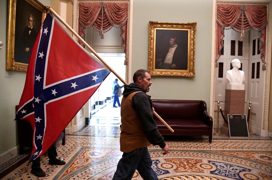 A rioter carries a Confederate battle flag on the second floor of the U.S. Capitol near the entrance to the Senate after breaching security defenses.