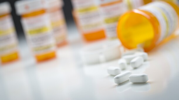 Variety of Medicine Bottles Behind Pills Spilling From Fallen Bottle.