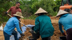 Air Force Master Sgt. Javier Martinez, left, and Vietnamese citizens fill buckets of soil during a Defense POW/MIA Accounting Agency (DPAA) mission in Quang Binh Province, Vietnam, March 29, 2026. The DPAA recovery team was searching for clues to locate the remains of troops who went missing in the Vietnam War.