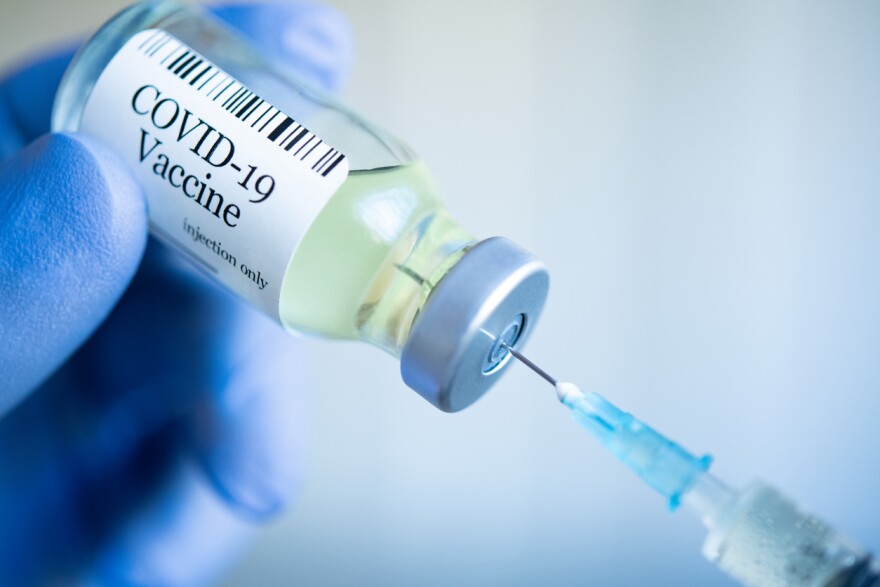 A syringe in a container labeled COVID-19 vaccine.