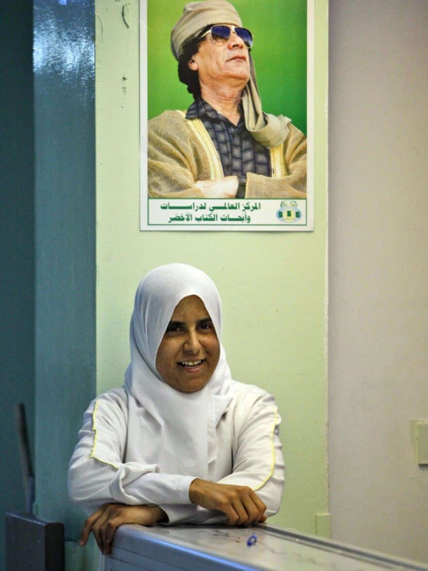 In this image taken during an organized trip by Libyan authorities, a hospital nurse stands in the lobby of the Zawiya teaching hospital, where rebels sought treatment during fighting. Above her, a portrait of Libyan leader Moammar Gadhafi.