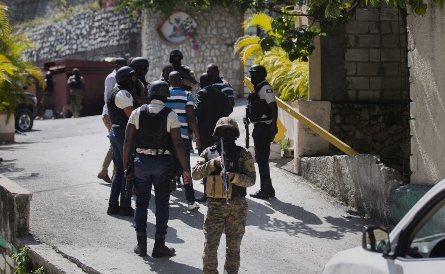 Security forces conduct an investigation as a soldier stands guard at the entrance to the residence of the Haitian president in Port-au-Prince on Wednesday.