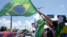 A protester waves a Brazilian flag over cars driving to the football stadium in Fortaleza, Northern Brazil, on June 19, 2013.