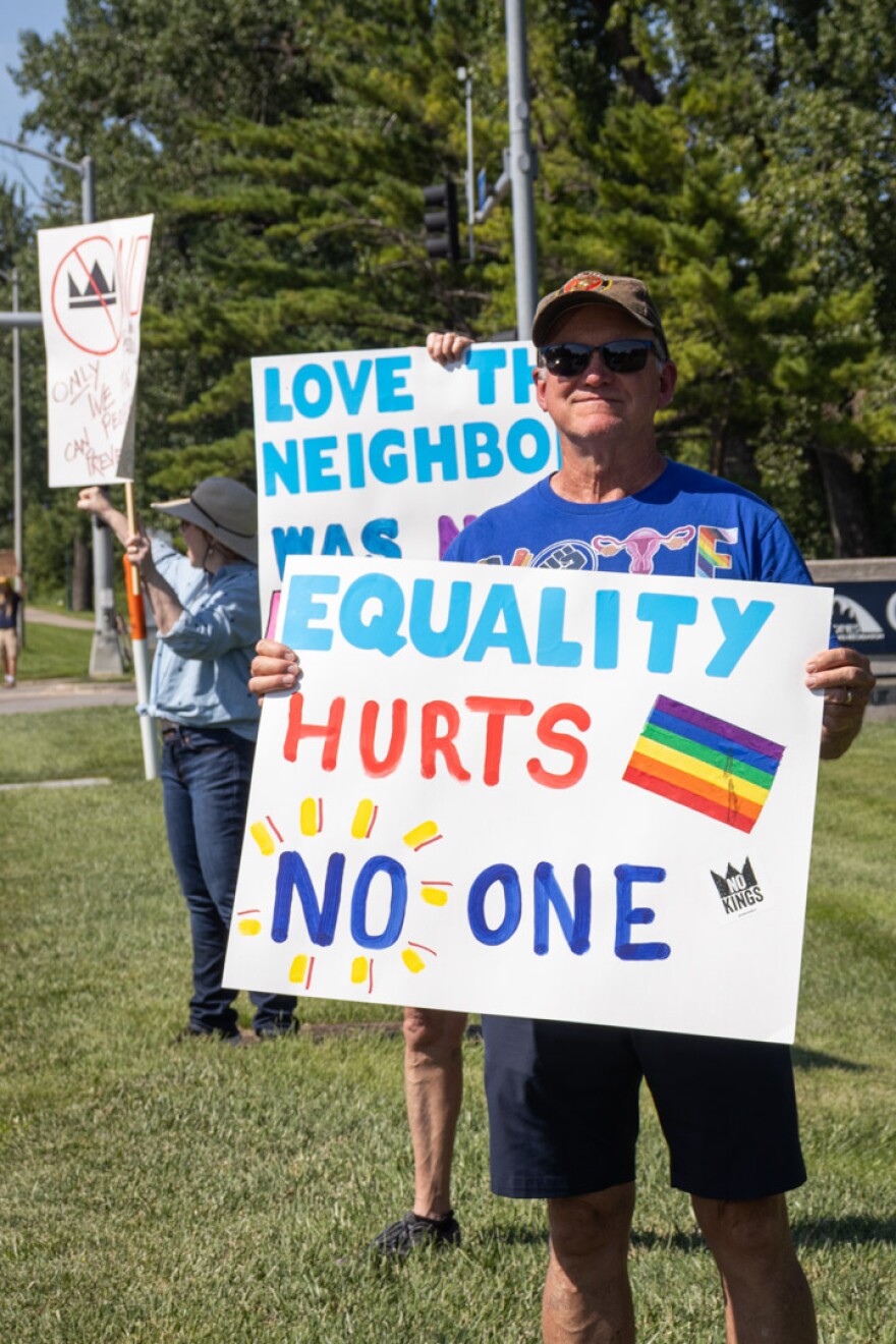 A man holds a sign that reads "Equality hurts no one."