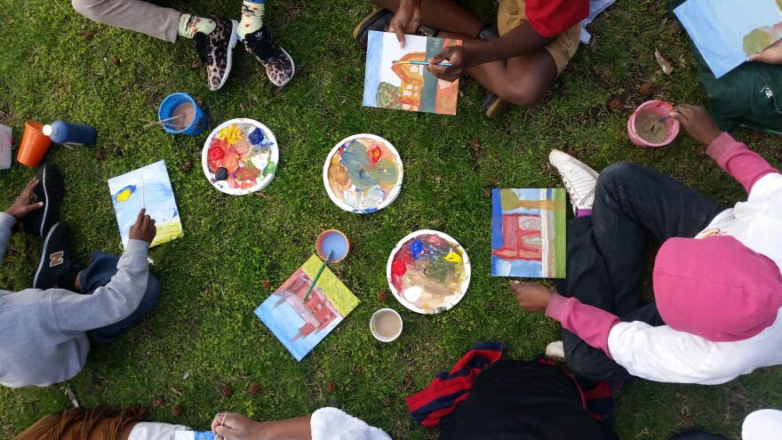 Four kids paint houses and other pictures on a grass background.