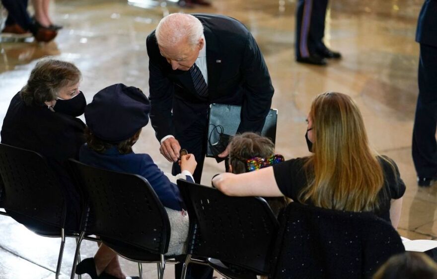 Biden presents a challenge coin to Logan Evans, the son of the slain officer.