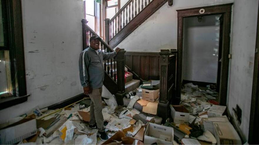 Lorenzo Savage, president of the Katherine Dunham Museum board, stands in the front room of the stone building. Despite all the damage to the building, most of the original woodwork is still present.