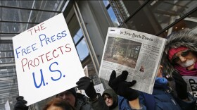 Protesters hold signs during a show of solidarity with the press in front of The New York Times building, Sunday, Feb. 26, 2017, in New York.