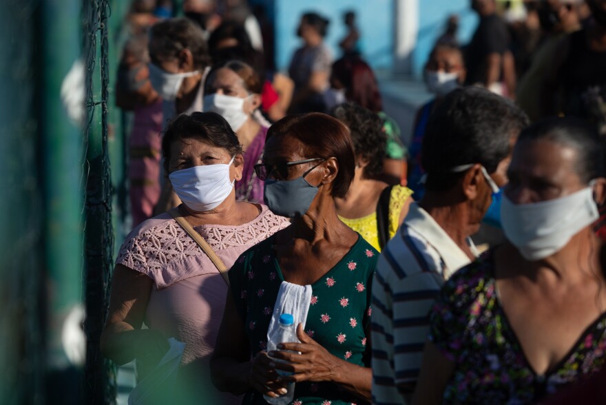 People line up for their COVID-19 vaccination in Duque de Caxias on March 22. After declaring he would never have the injection, Brazilian President Jair Bolsonaro now touts his health ministry's vaccination efforts, and claims Brazil will acquire "400 million doses" this year. Even if true, that is too late, says Margareth Dalcomo, a respiratory physician and researcher.