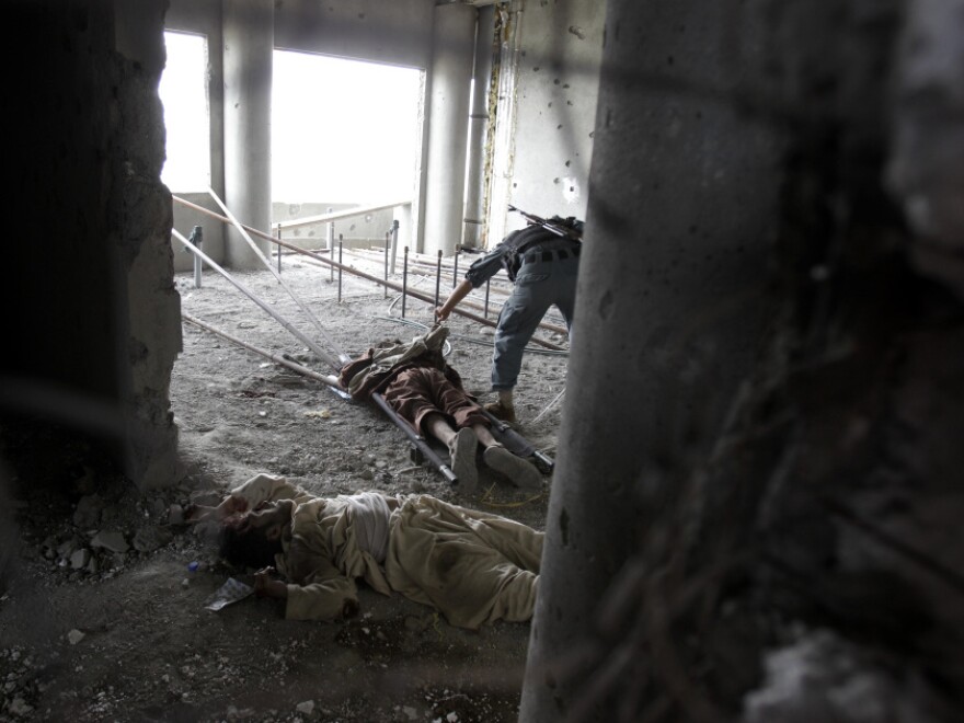 Inside the building from which the attack was staged, an Afghan soldier checked one attacker's body earlier today. Another dead insurgent lies nearby. Bullet holes riddle the walls.