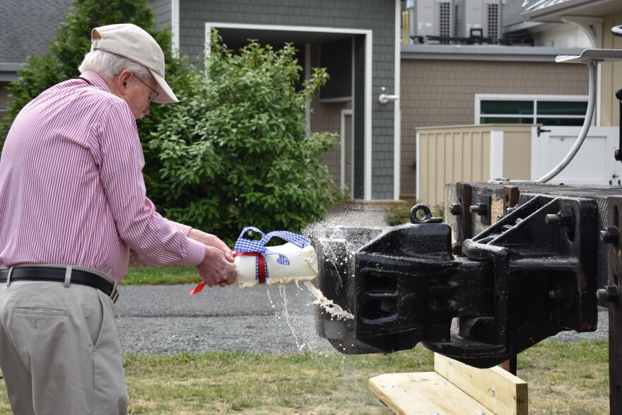 Joe Stewart smashes a bottle of lager on part of the restored number 60 steam engine to christen it