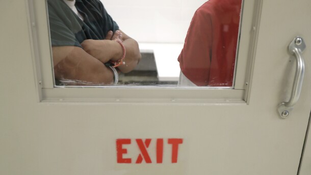A view of two people through a glass window of a door that reads "exit only."