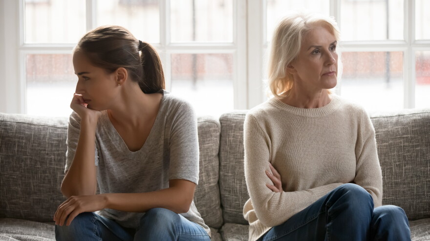 In quarrel elderly mother grown up daughter sit on couch separately having conflict, intergenerational misunderstanding, adult grandchild grandma difficult bad relations different generations concept
