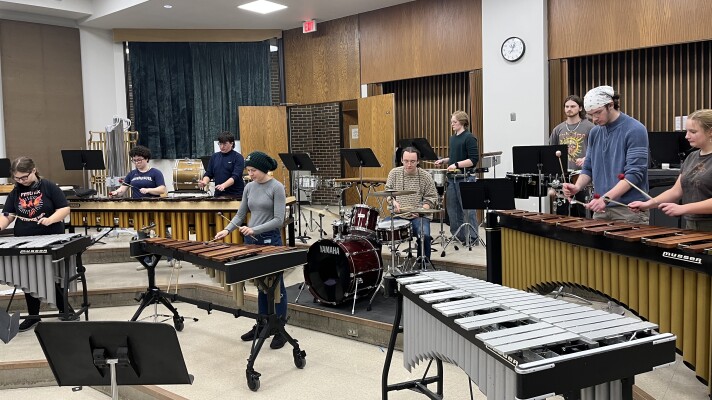 A group of people playing on xylophones, marimbas, and drum kits.