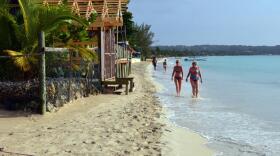 Sunbathers walk along a badly eroding patch of resort-lined crescent beach in Negril in western Jamaica. (David McFadden/AP)