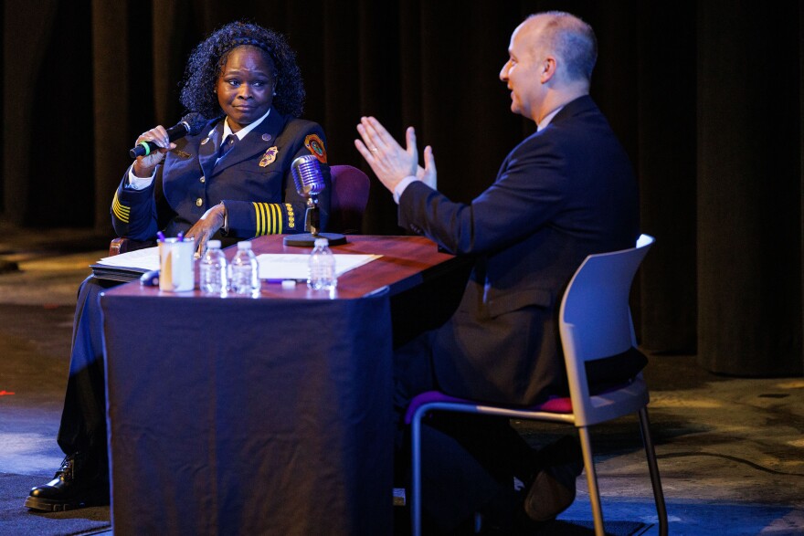 Lansing Fire Chief Carrie Edwards-Clemons, left, speaks during Lansing Mayor Andy Schor's State of the City Address at Dart Auditorium in Lansing, Mich., on March 18, 2026. Rather than giving a traditional speech, Schor, right, sat behind a talk show style desk and invited city staff to provide updates on their departments' achievements from the past year.
