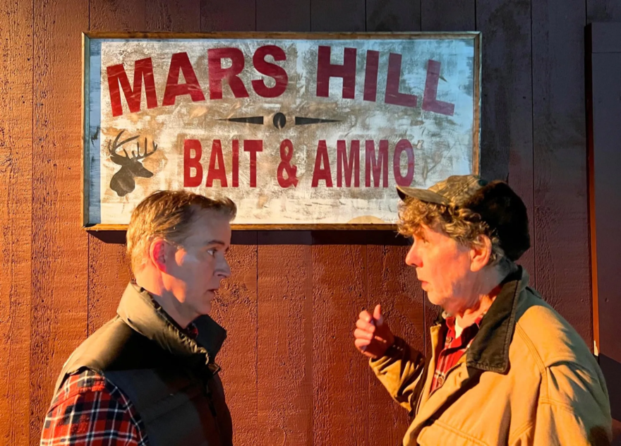 A still from Mars Hill: Bait and Ammo: Two men stand in front of a sign that reads "Mars Hill Bait & Ammo."