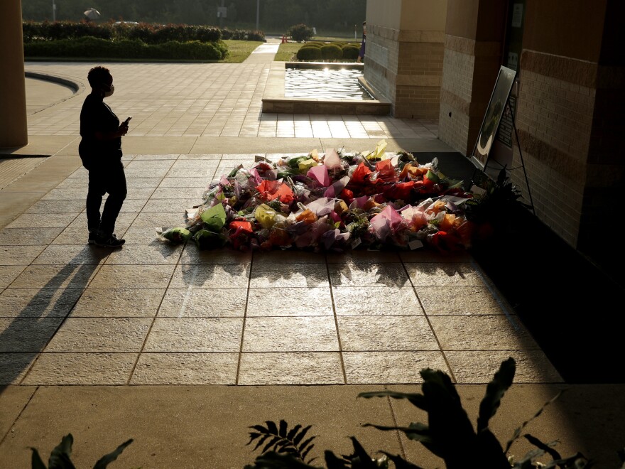 A woman stops to photograph a memorial Tuesday for Floyd at The Fountain of Praise church in Houston.